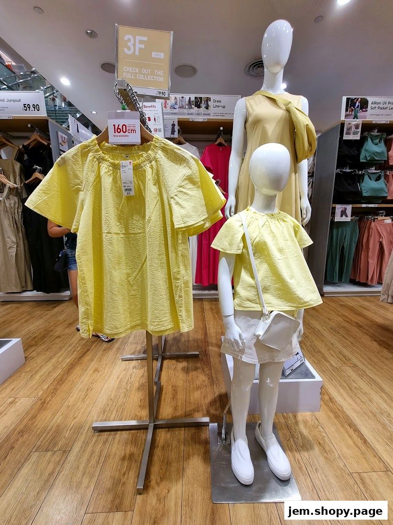 Yellow tops displayed on mannequins and a rack in a UNIQLO store.