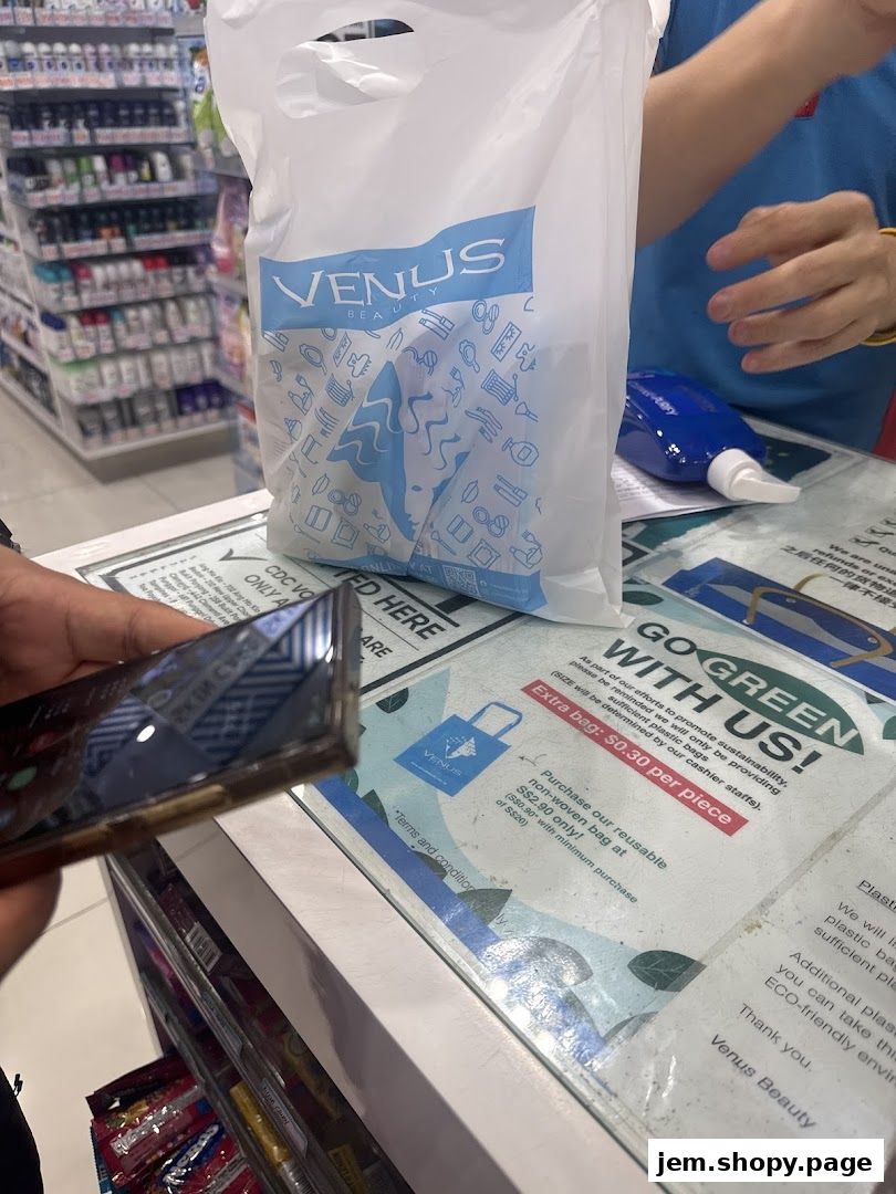 A shopping bag from Venus Beauty is placed on a counter with promotional signs.