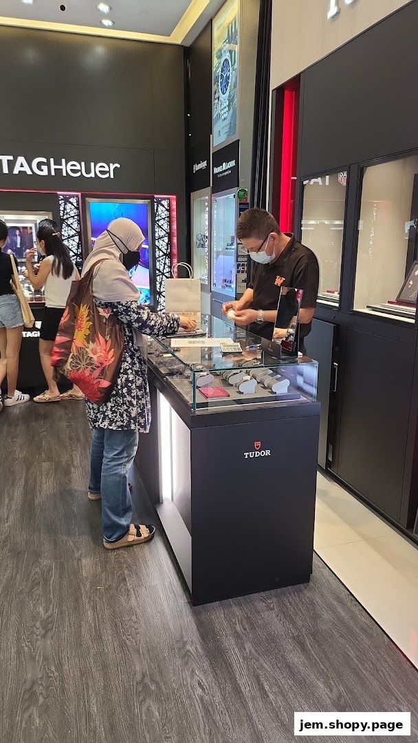 A customer is being assisted by a sales associate at a watch retailer displaying Tudor and TAG Heuer brands.