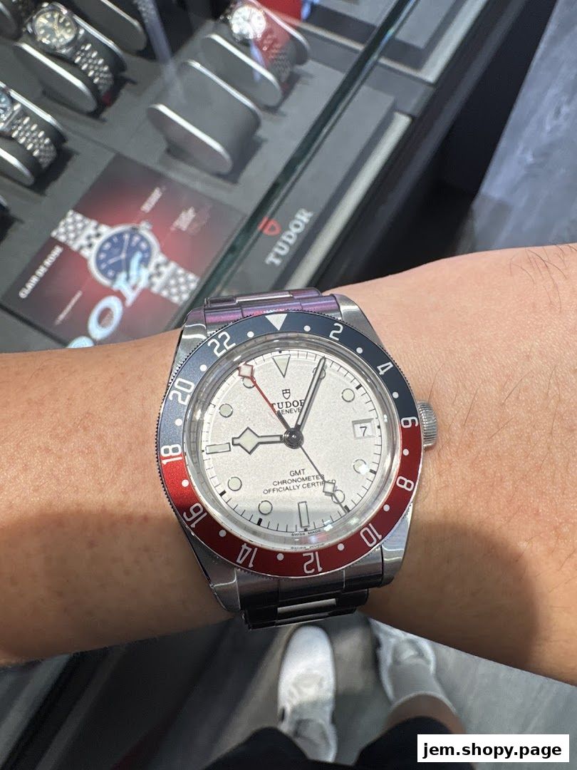 A person wearing a Tudor GMT watch with a red and blue bezel in a watch store.