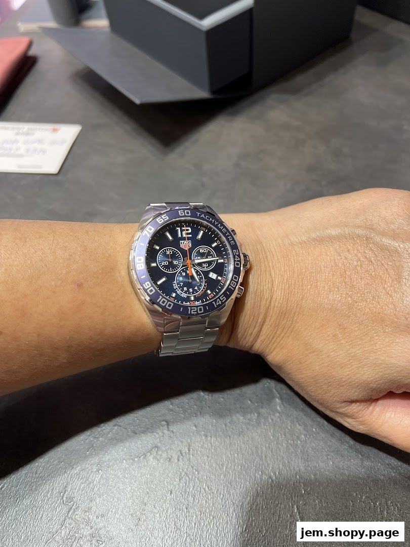 A person wears a TAG Heuer watch with a blue dial and silver band.
