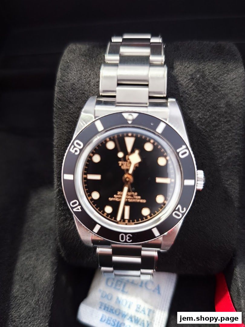 A close-up shot of a luxury Tudor watch with a black dial and stainless steel bracelet.