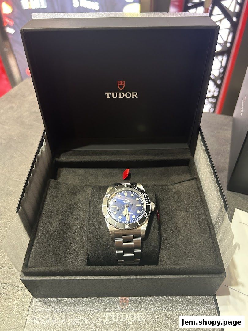 A Tudor watch in its presentation box, showcasing its blue dial and stainless steel bracelet.