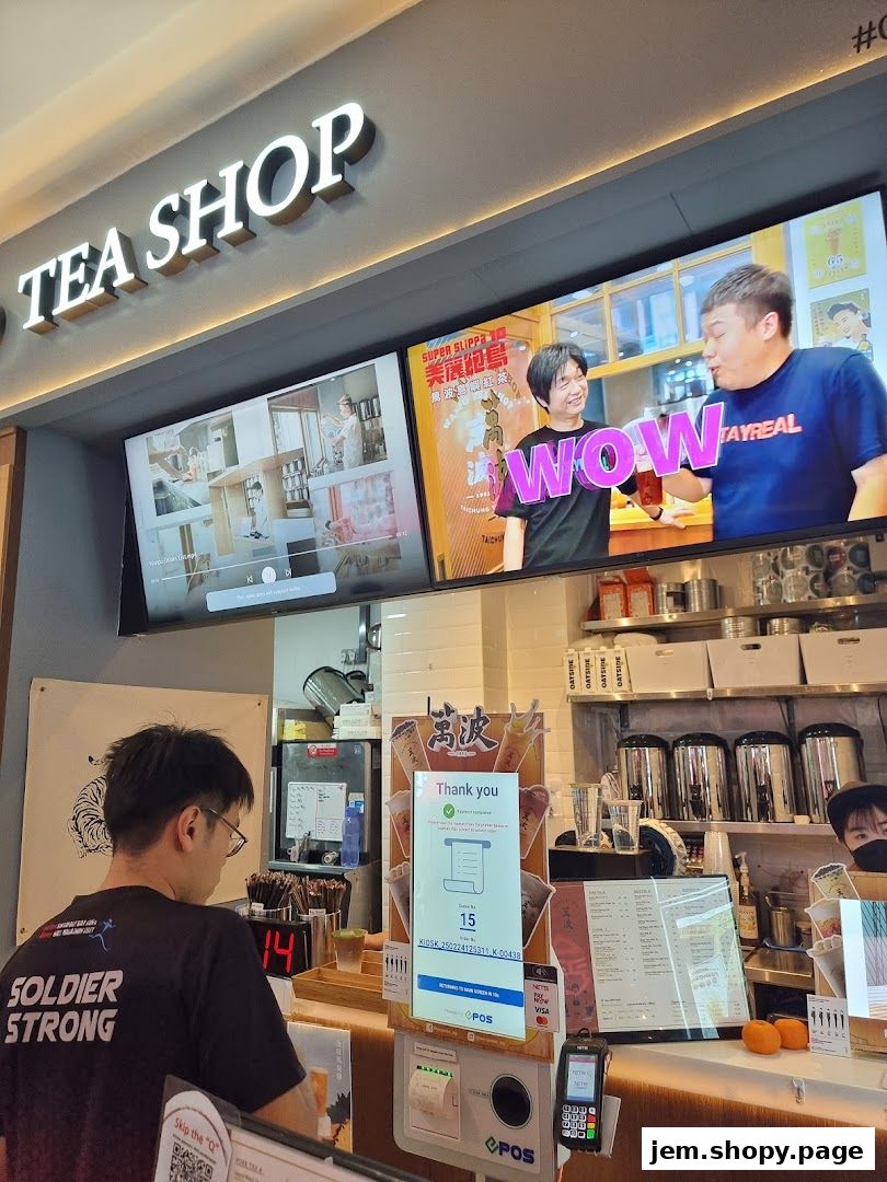 Wanpo Tea Shop interior with staff, screens displaying ads, and a menu board.