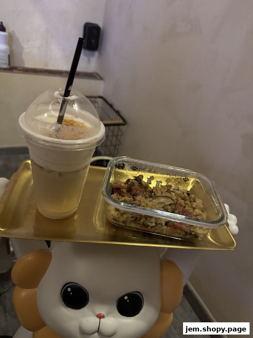 A golden tray holds a drink and a container of food, presented on a decorative stand.