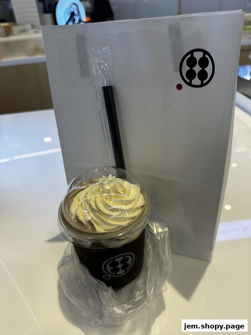 A takeaway drink with whipped cream and a branded paper bag from Warabimochi Kamakura.
