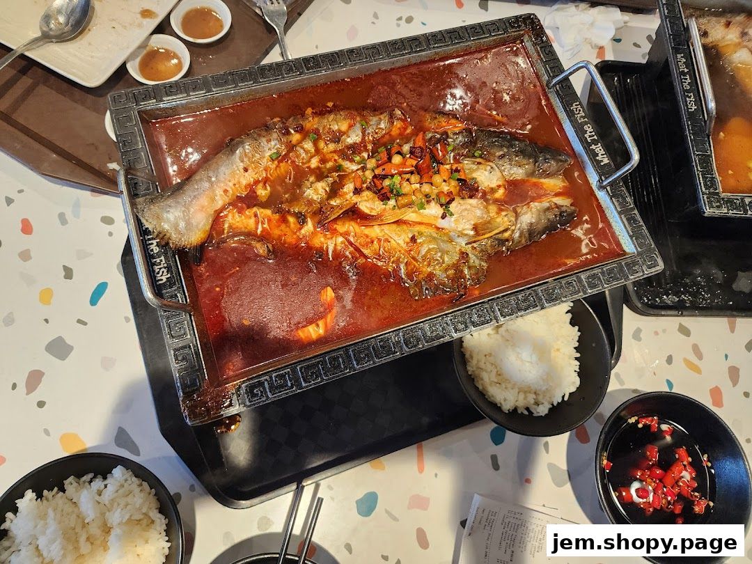 A whole fish cooked in spicy sauce with rice and dipping sauce.