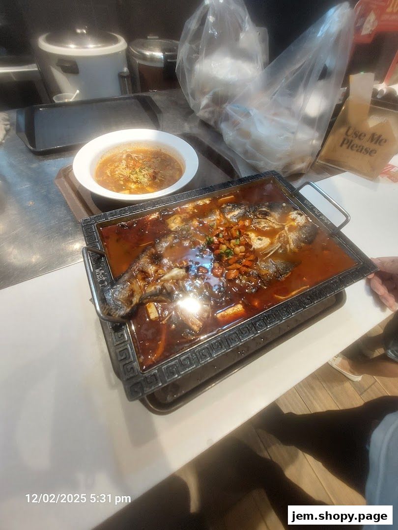 A whole fish dish in a spicy sauce served with a side of soup and takeout bags.