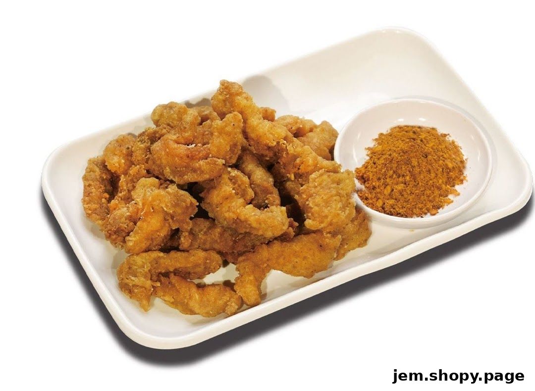 A plate of crispy fried chicken pieces with a side of seasoning powder.