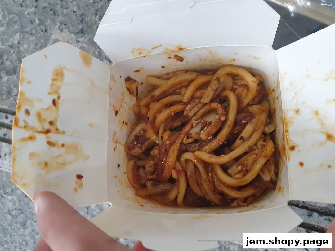 A close-up shot of a takeaway box filled with delicious-looking noodles.