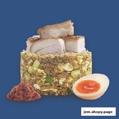 A serving of fried rice topped with chicken pieces, served with chili paste and a halved egg.