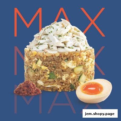 A tall serving of fried rice topped with crab meat, served with a side of chili paste and a halved soft-boiled egg.
