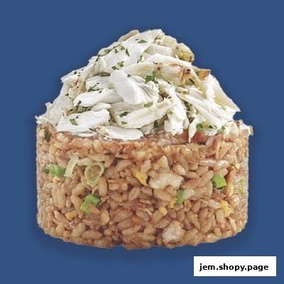 A close-up of a cylindrical serving of fried rice topped with shredded crab meat and parsley.