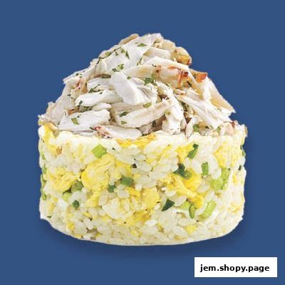 A close-up of a cylindrical serving of fried rice topped with shredded crab meat.