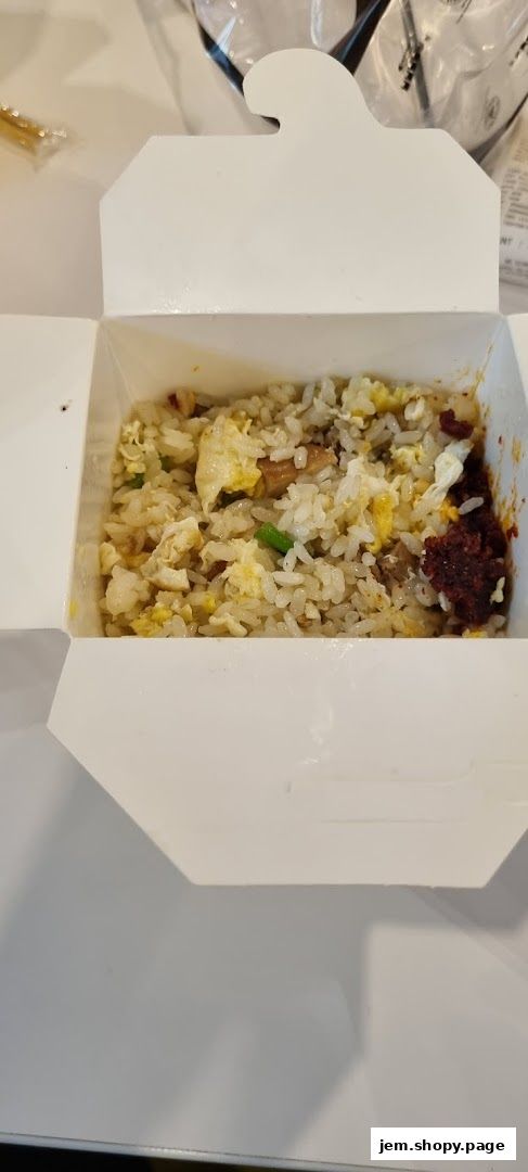 A white takeout box filled with fried rice, egg, and meat.
