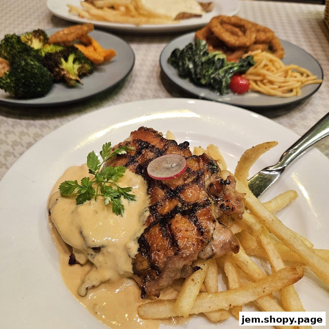 A plate of grilled chicken with fries and sauce, with other dishes in the background.