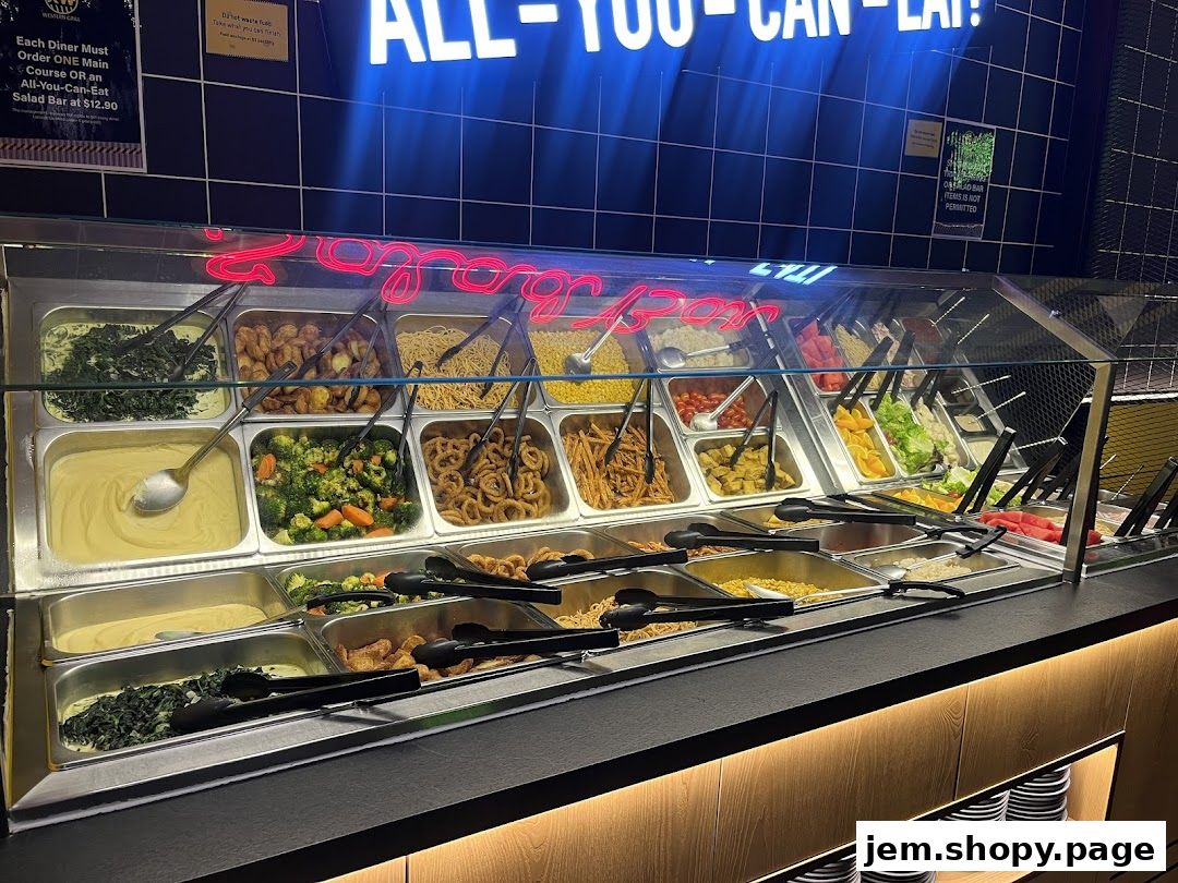 A buffet display with various food items in metal trays under a glass counter.