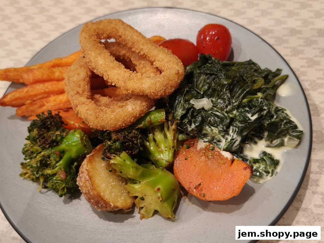 A plate of food featuring onion rings, sweet potato fries, broccoli, spinach, and tomatoes.