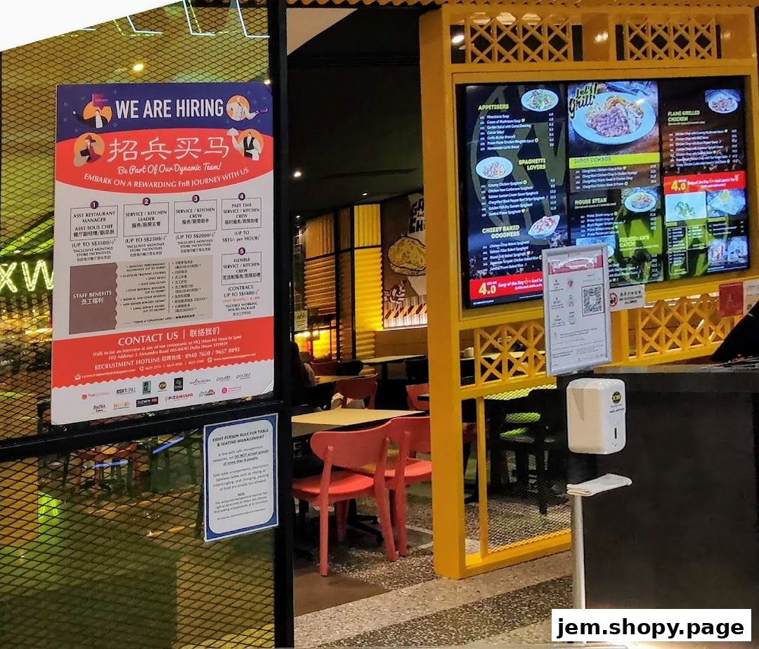 A digital menu board displays food items and a hiring poster is visible on the left.