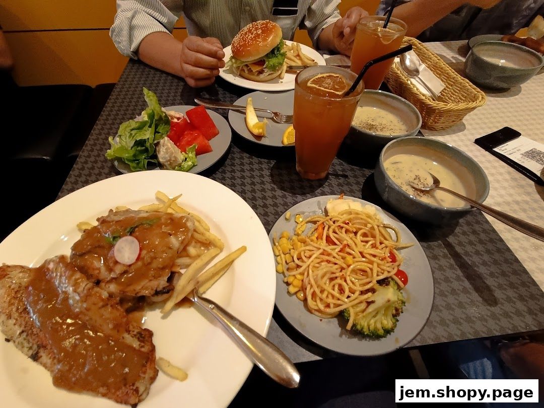 A table laden with various dishes including steak, pasta, soup, salad, and drinks.