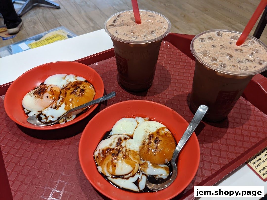 Two bowls of soft-boiled eggs with soy sauce and pepper, and two iced coffee drinks.