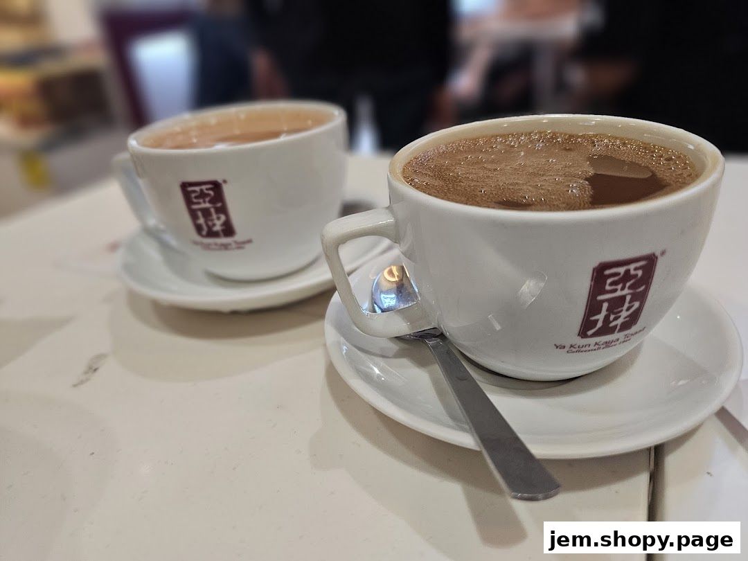 Two cups of coffee with the Ya Kun Kaya Toast logo on a white table.