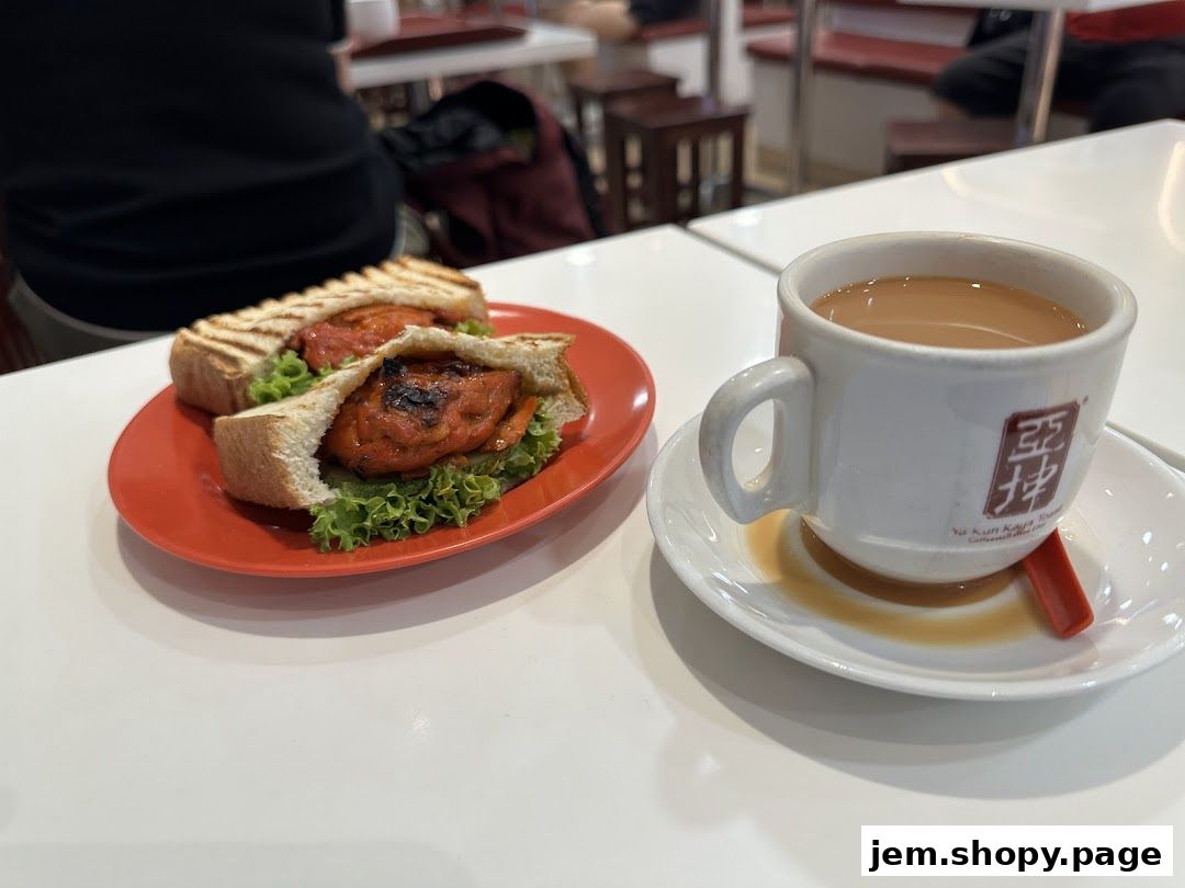 A sandwich and a cup of tea are served on a white table at Ya Kun Kaya Toast.