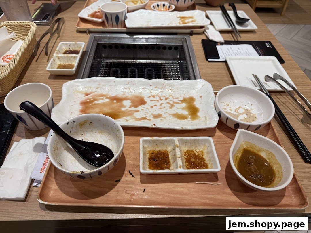 A table setting with used plates, bowls, and dipping sauces after a meal.