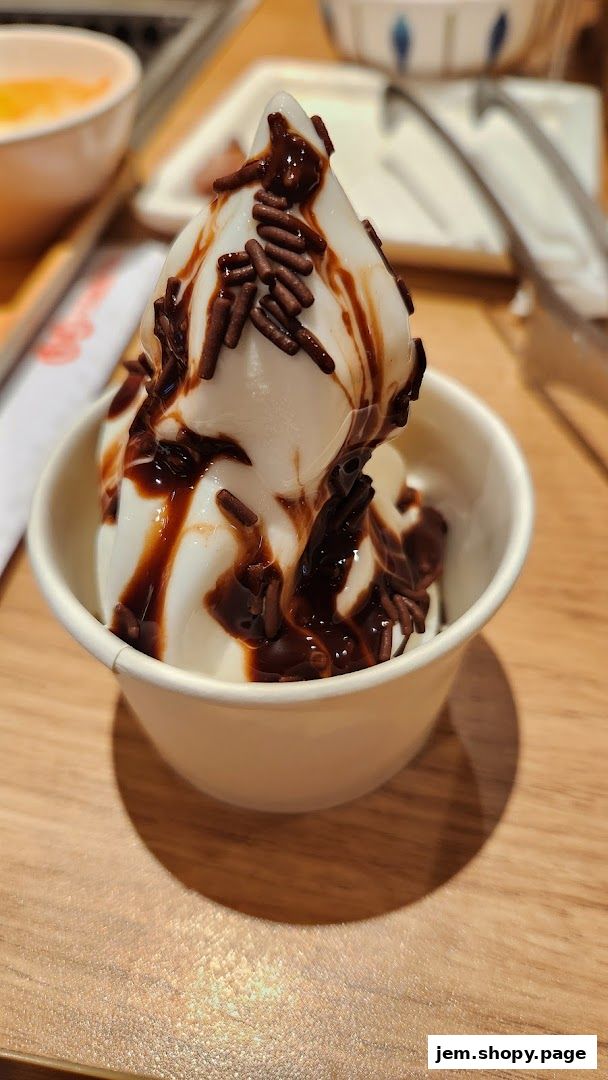 A close-up of a soft-serve ice cream cone drizzled with chocolate sauce and sprinkles.