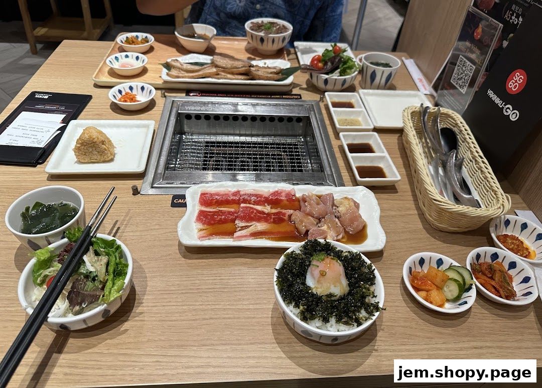 A table set for a Yakiniku meal with raw meats, rice, salad, and side dishes.