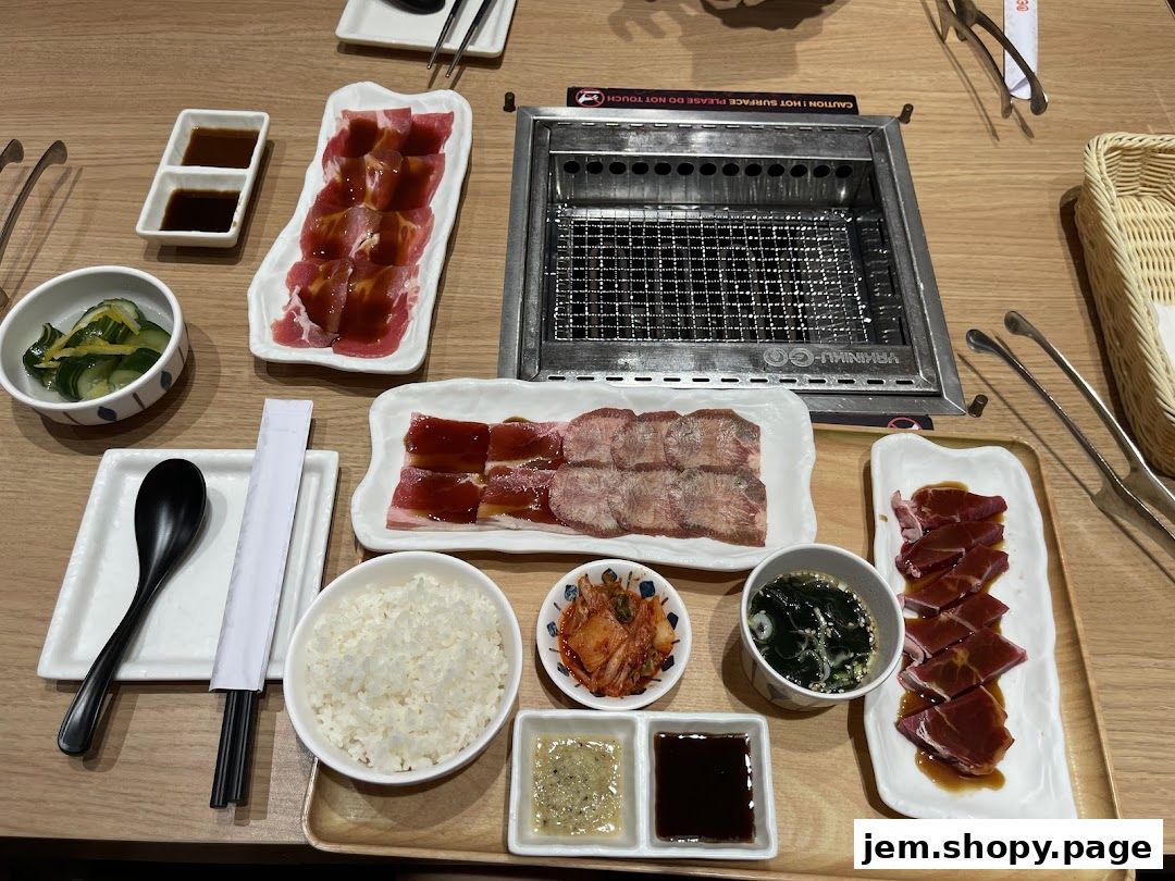 A table set for a yakiniku meal with various cuts of meat, rice, and side dishes.