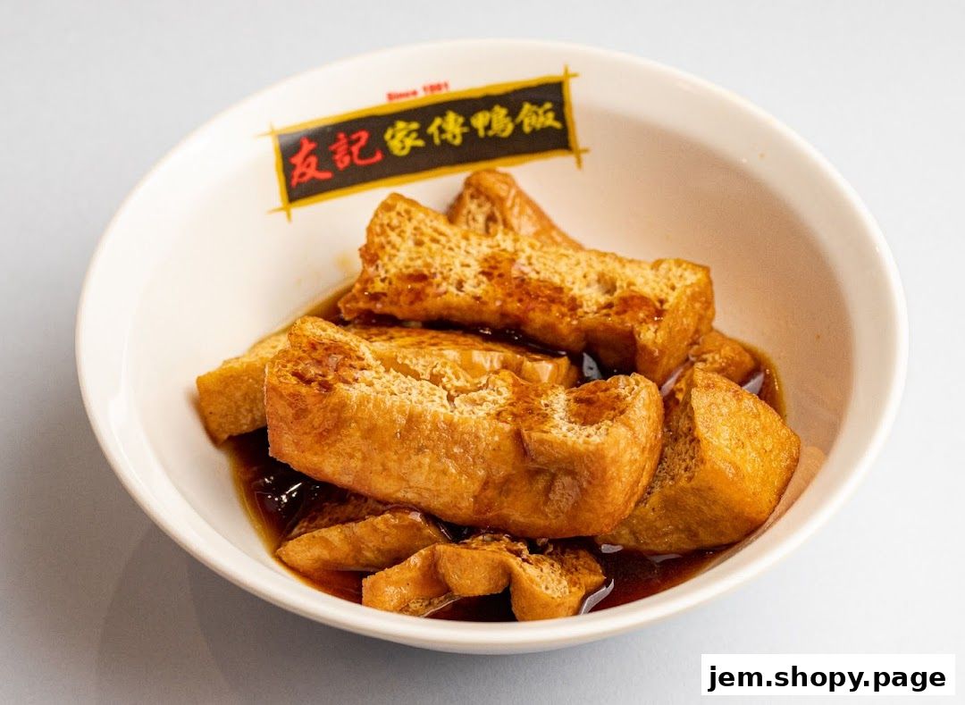 A bowl of braised tofu puffs in a savory sauce, with the restaurant's logo visible.