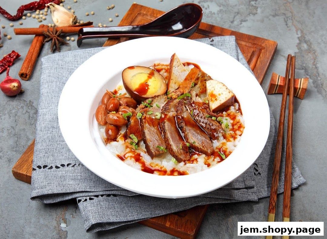 A bowl of congee with sliced duck, braised egg, peanuts, and tofu, garnished with scallions and sauce.