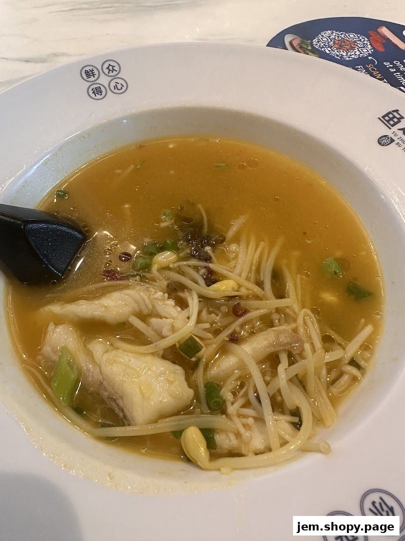 A bowl of fish noodle soup with enoki mushrooms and green onions.