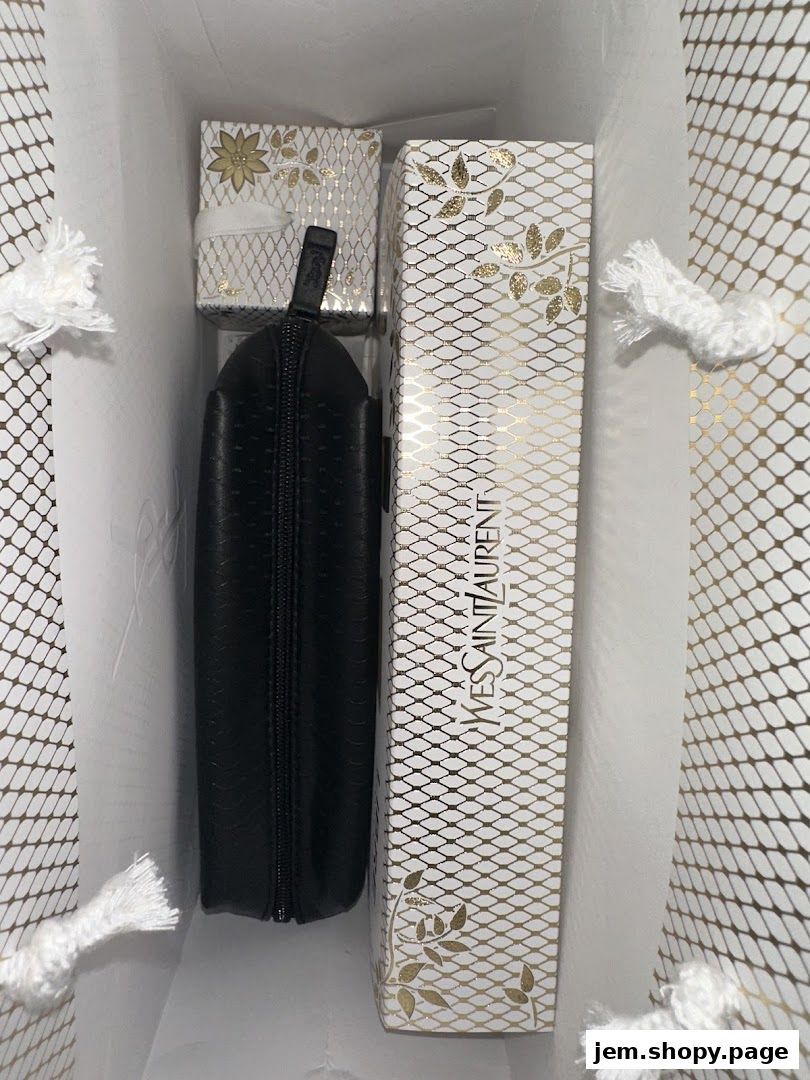 A YVES SAINT LAURENT branded gift bag containing a black makeup bag and two gift boxes.