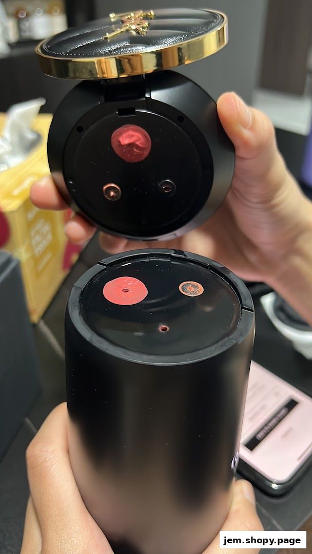 Hands holding YSL makeup products with swatches of lipstick.