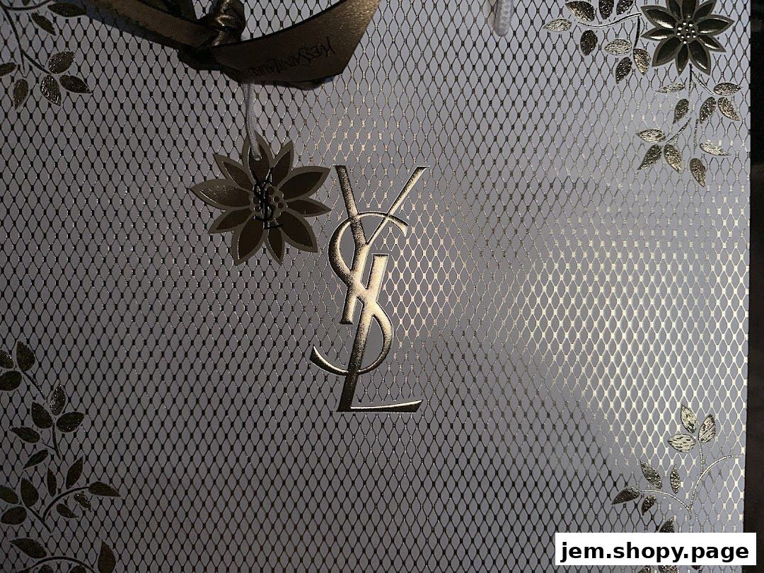 The iconic YSL logo on a textured background with floral accents and ribbon.