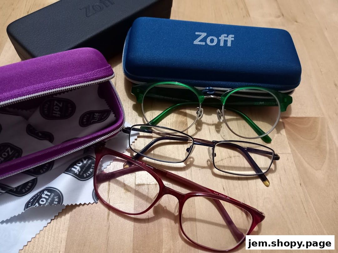 Three pairs of Zoff eyeglasses with cases and cleaning cloths on a wooden surface.