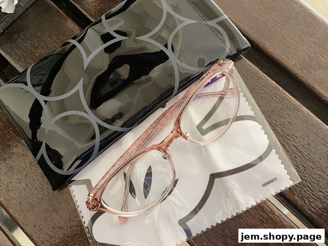 A pair of pink glasses with a black case and a Disney-themed cleaning cloth.