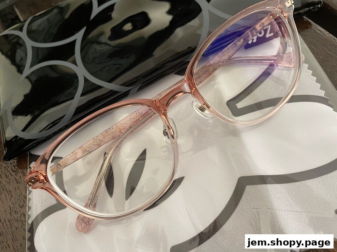 Close-up of stylish pink Zoff eyeglasses with a patterned case and cleaning cloth.