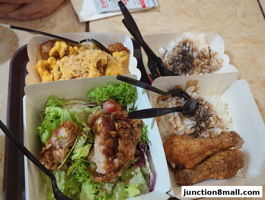 A close-up shot of three takeaway boxes filled with crispy chicken meals and rice.