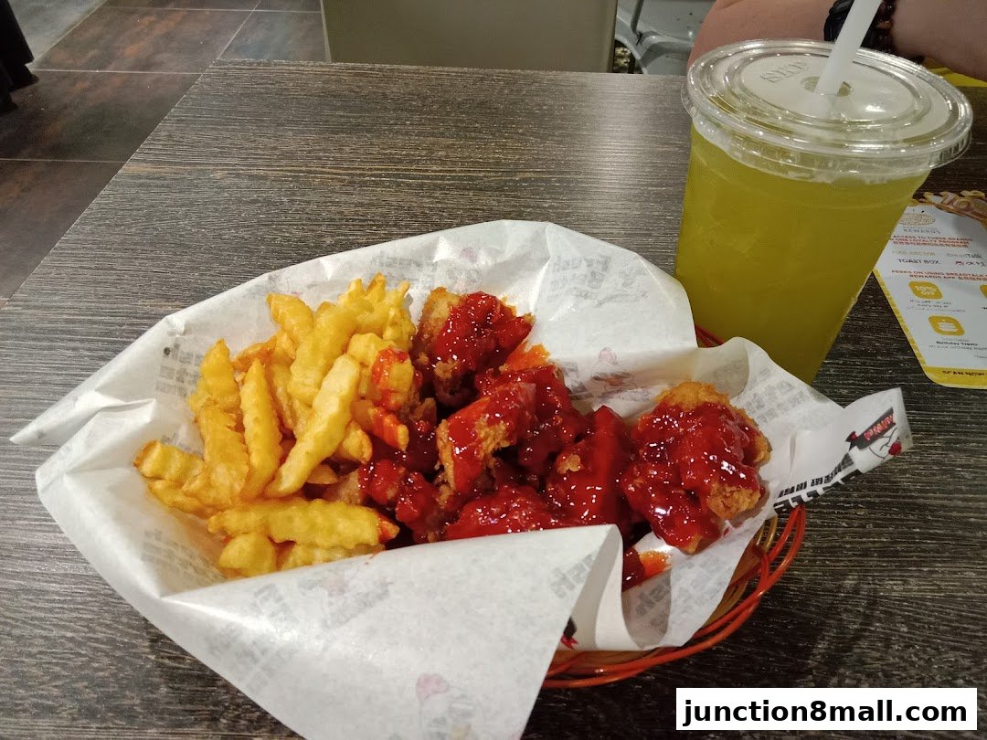 A basket of fried chicken wings with fries and a yellow drink.