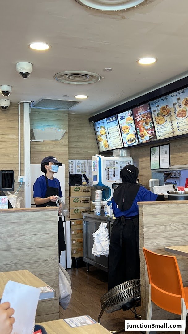 Two employees work behind the counter at Long John Silver's, with menus displayed above.