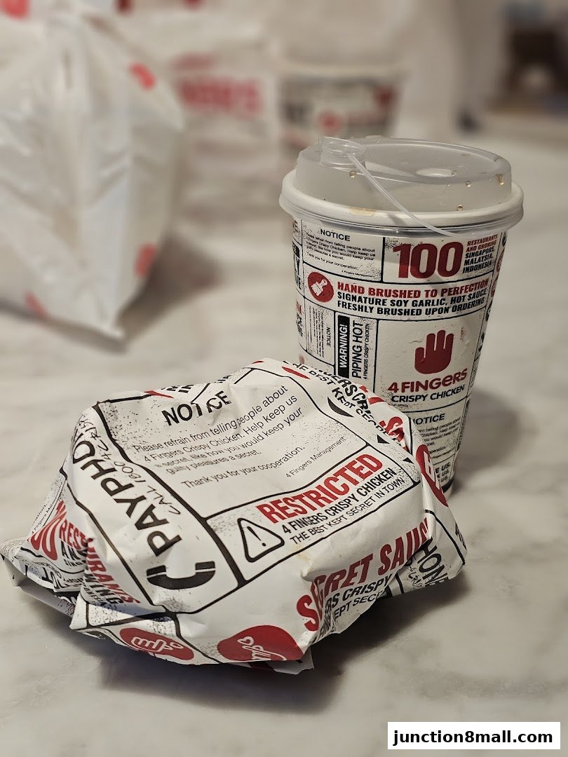 A wrapped chicken burger and a drink cup from 4 Fingers Crispy Chicken.