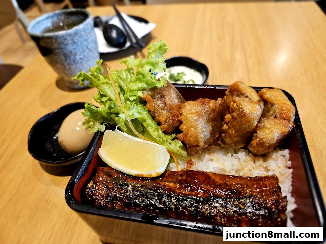 A bento box with grilled eel, fried chicken, rice, a boiled egg, and salad.
