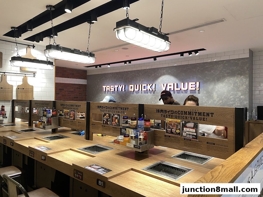 Interior of a Yakiniku Like restaurant with individual grilling stations and a prominent "TASTY! QUICK! VALUE!" sign.