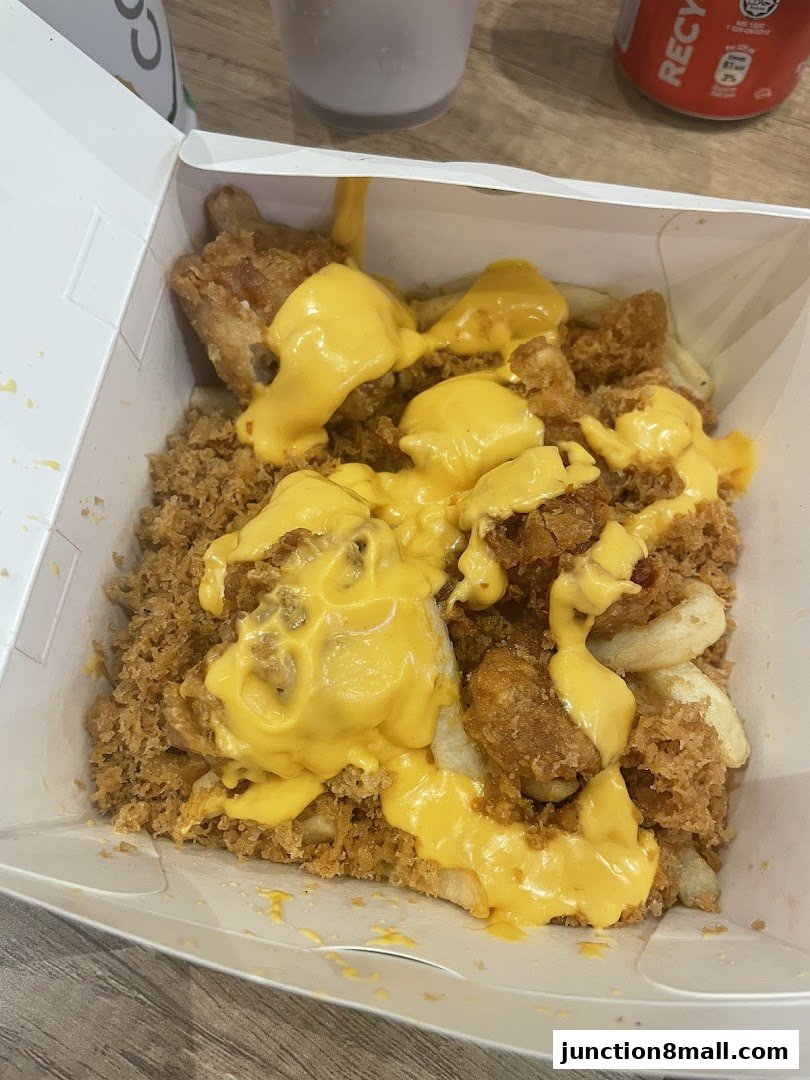 A box of crispy chicken pieces and fries generously topped with melted cheese.