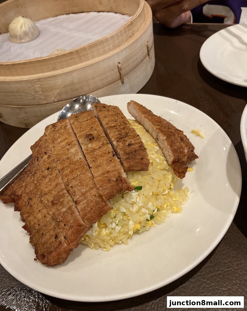 A plate of pork chop fried rice with a dim sum basket in the background.