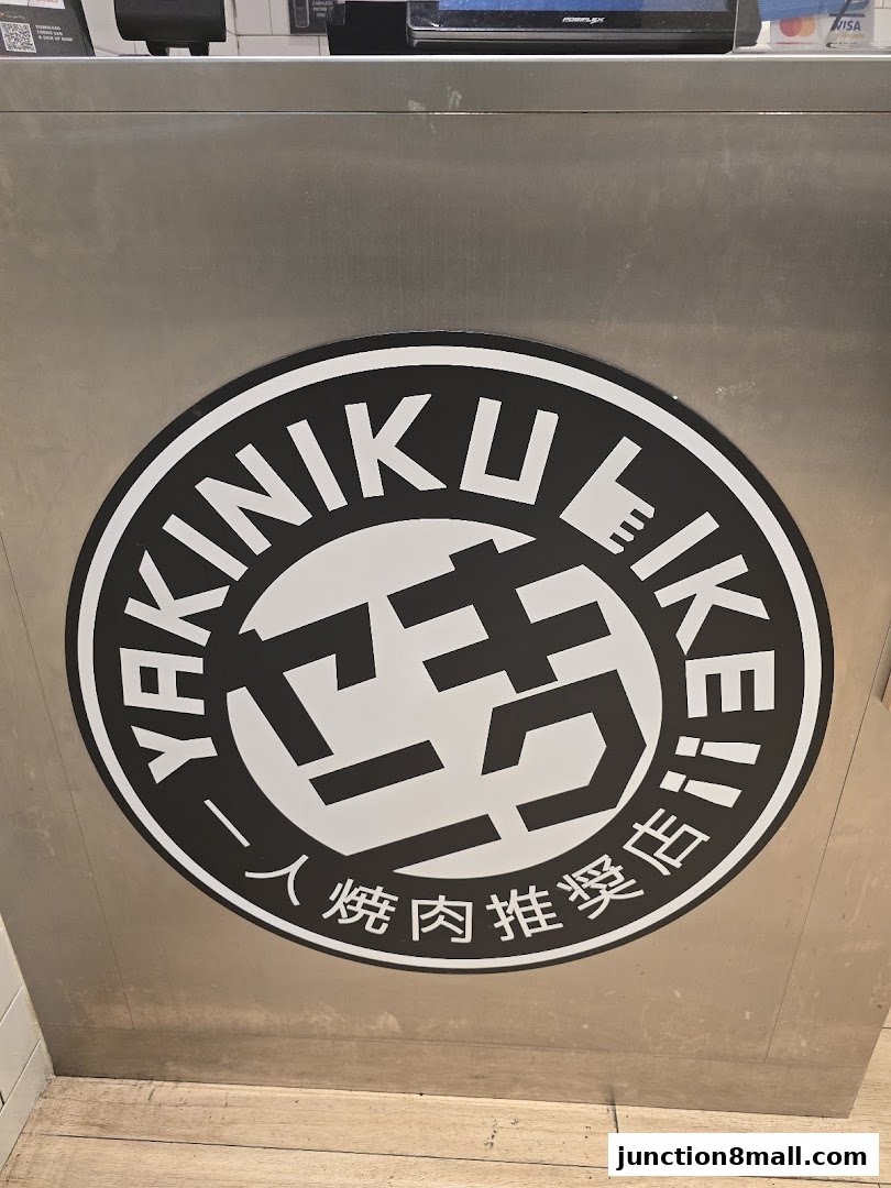 A close-up of the Yakiniku Like Junction 8 logo on a stainless steel surface.