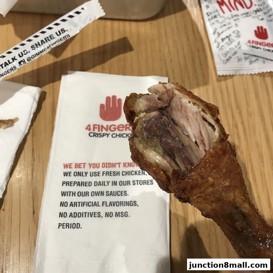 A close-up of a crispy chicken drumstick with a napkin detailing the restaurant's commitment to fresh ingredients.